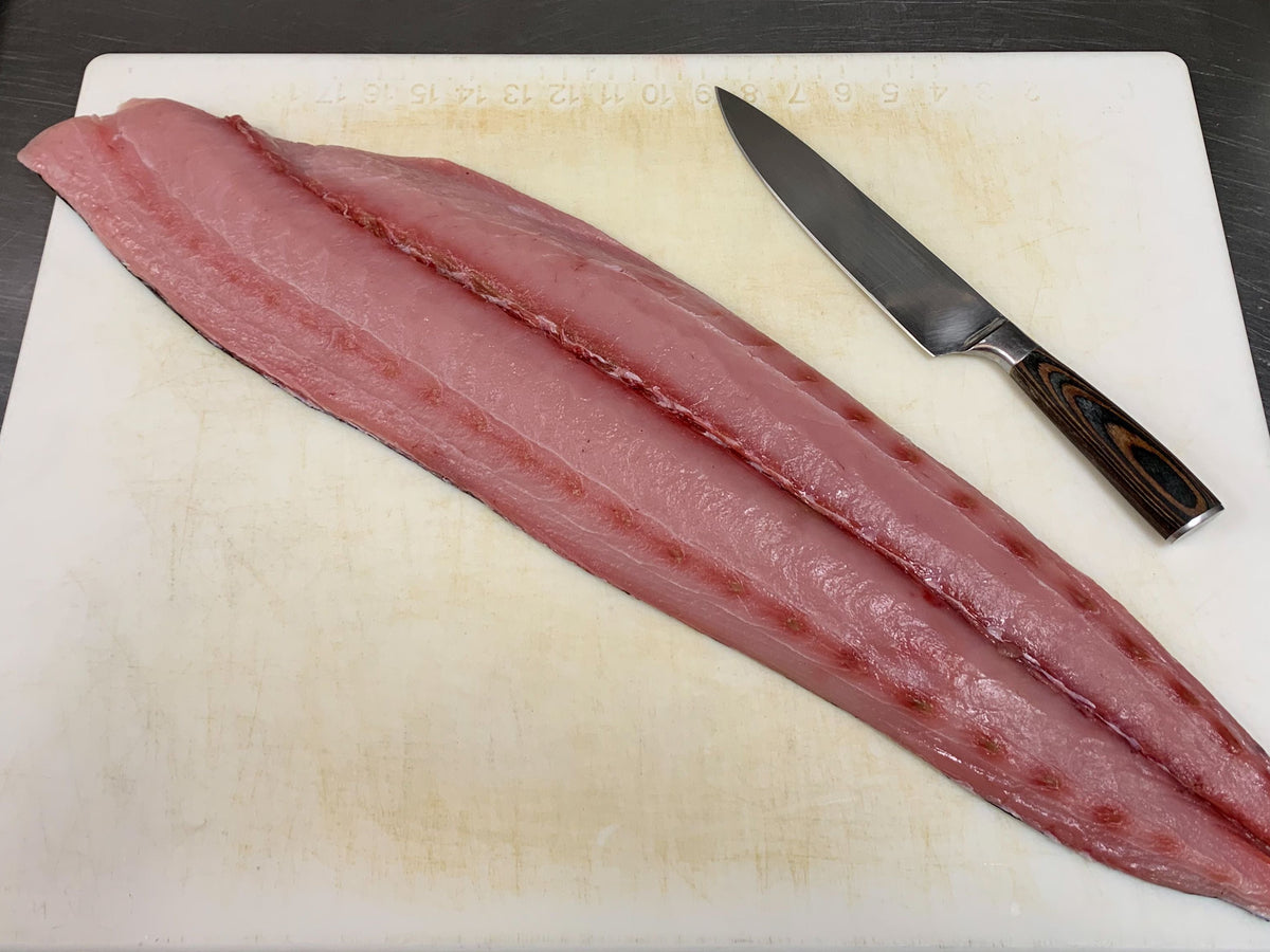 Raw fish fillet on a cutting board with a knife
